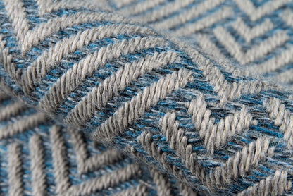 Close-up of blue & white chevron woven rug with thick, textured yarns.