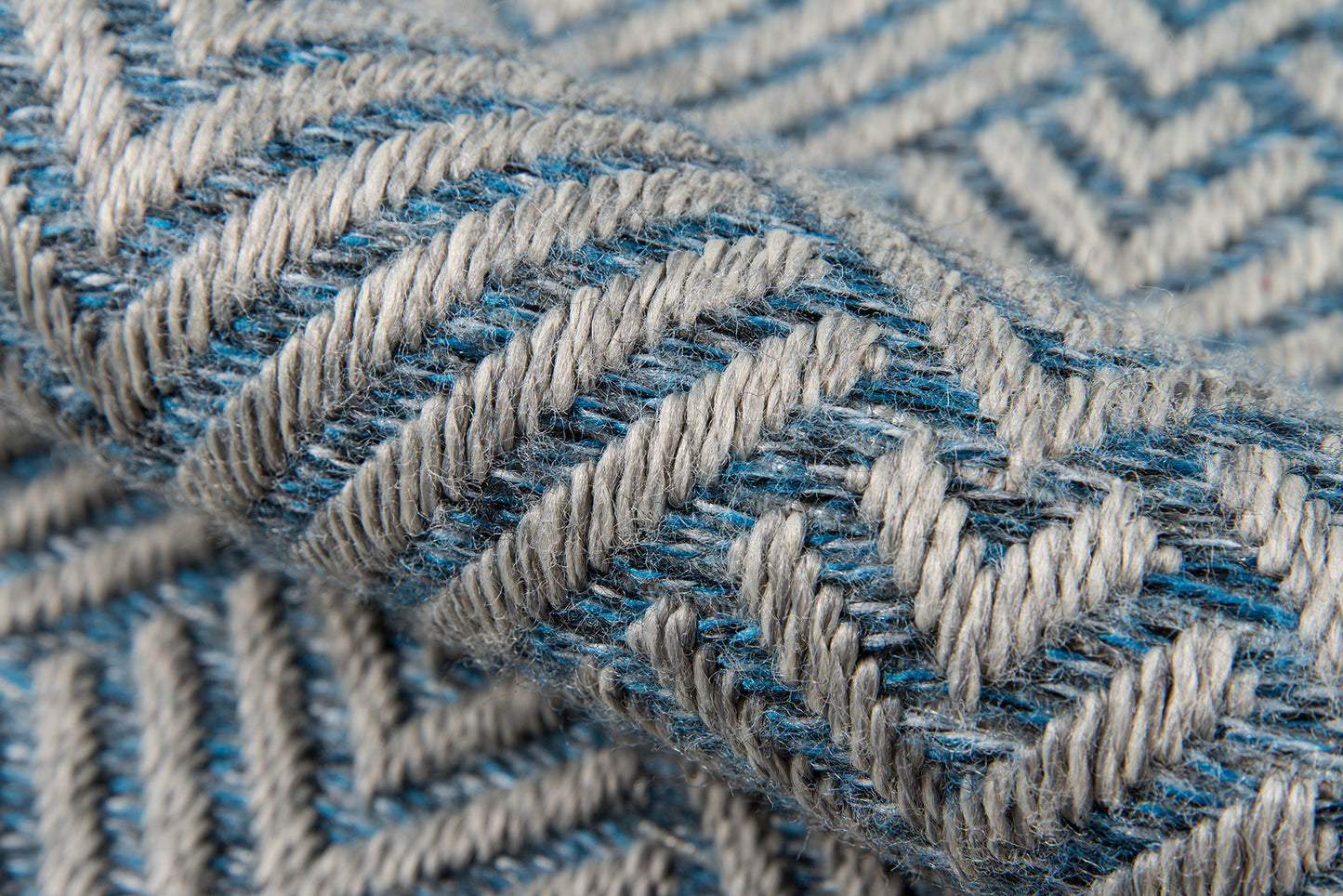 Close-up of blue and light gray woven textile with chevron pattern and chunky yarn texture.