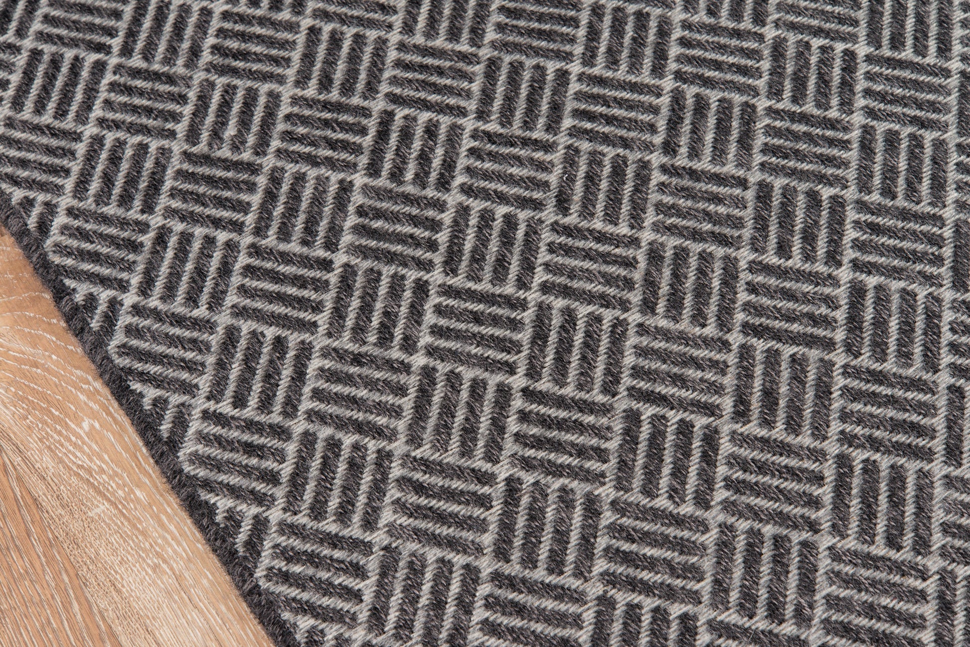 Dark gray and light gray geometric patterned rug on a wood floor.