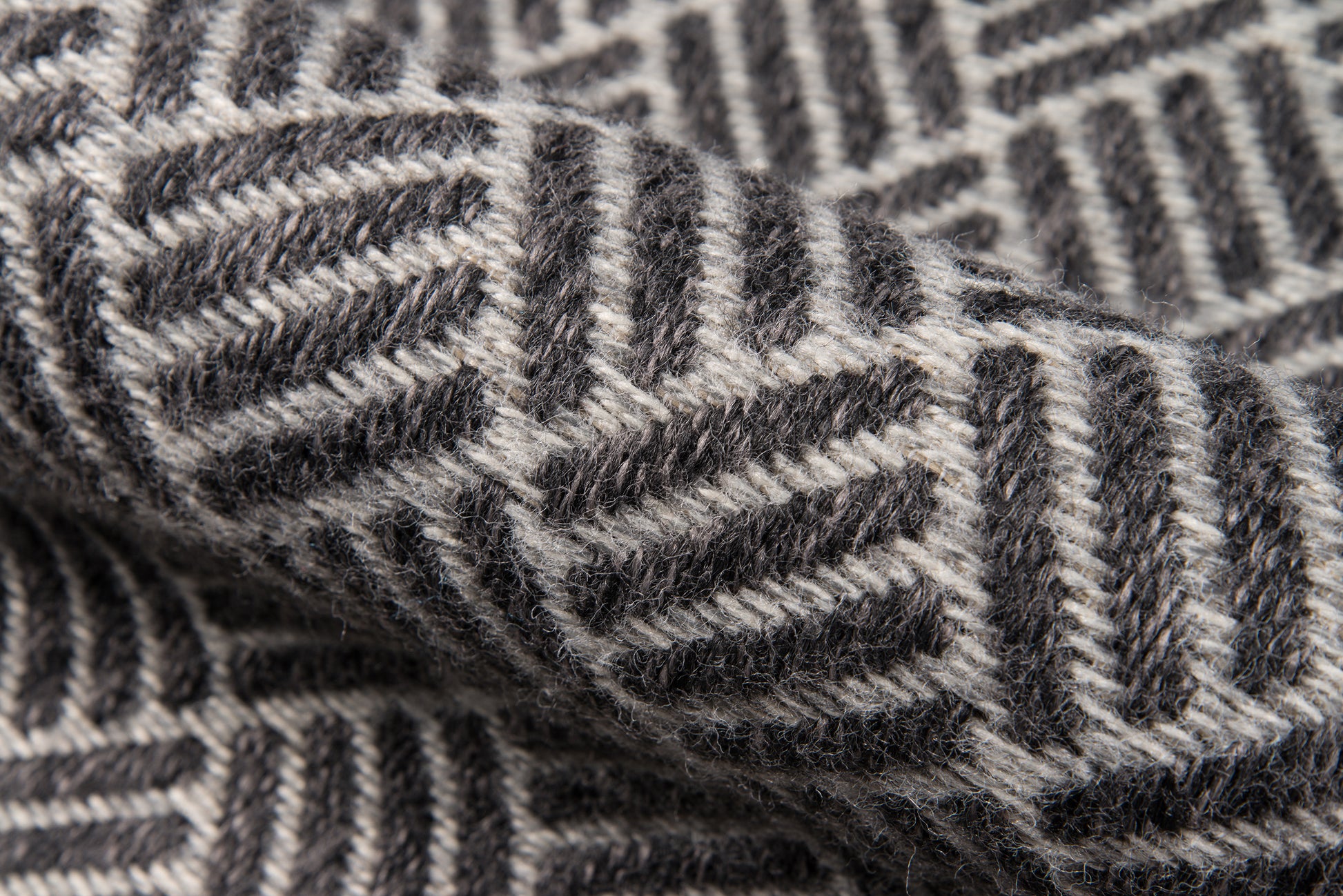 Close-up of gray and charcoal chevron rug texture; soft floor rug with bold geometric pattern.