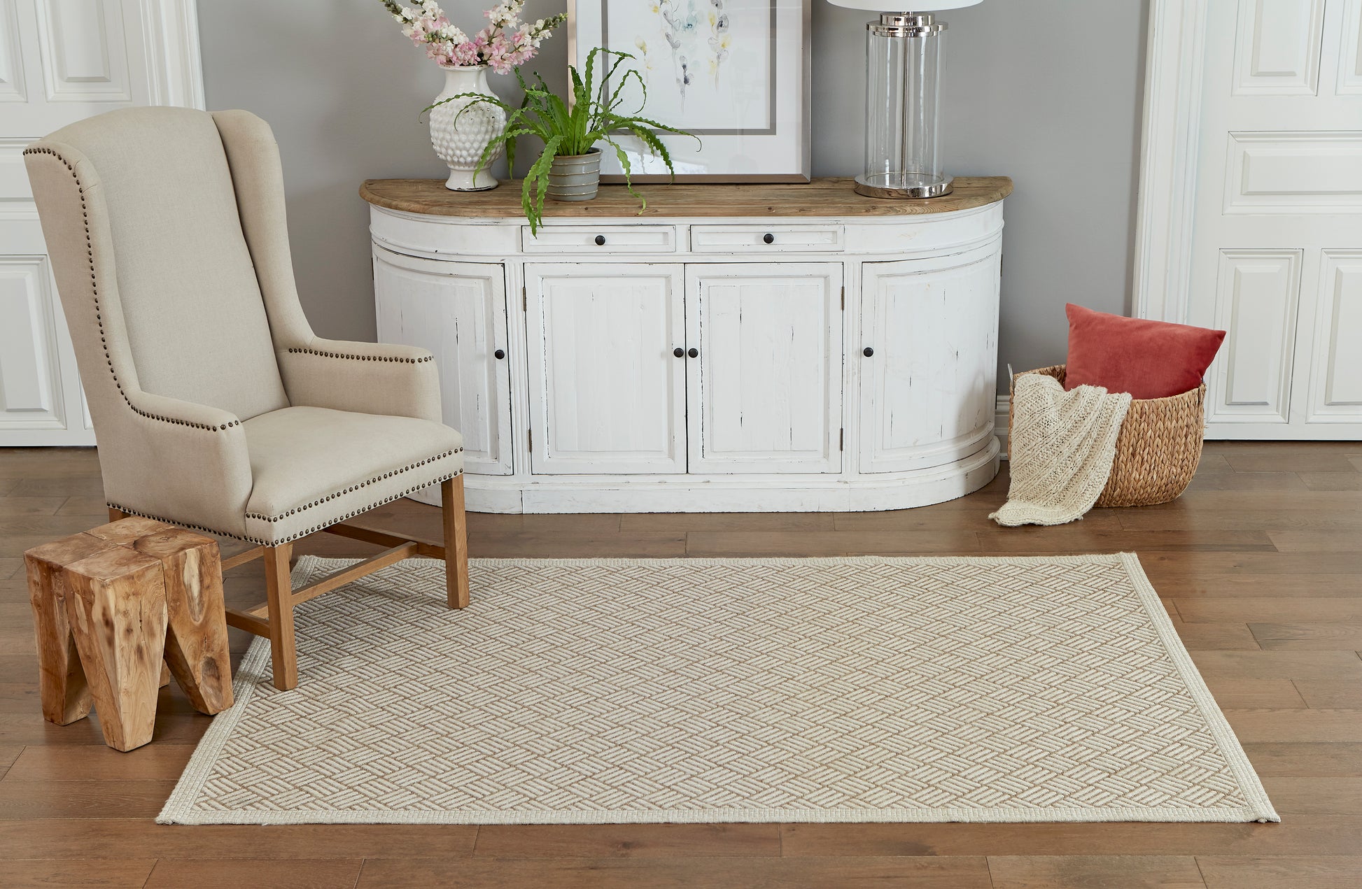 Tan rectangular woven area rug with subtle geometric pattern on hardwood floor in a coastal-style living room.