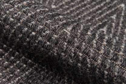Close-up of charcoal gray tweed rug with a subtle heathered weave & speckled white fibers.