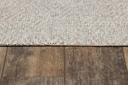 Gray geometric woven rug with a diamond pattern on dark brown wood floor.