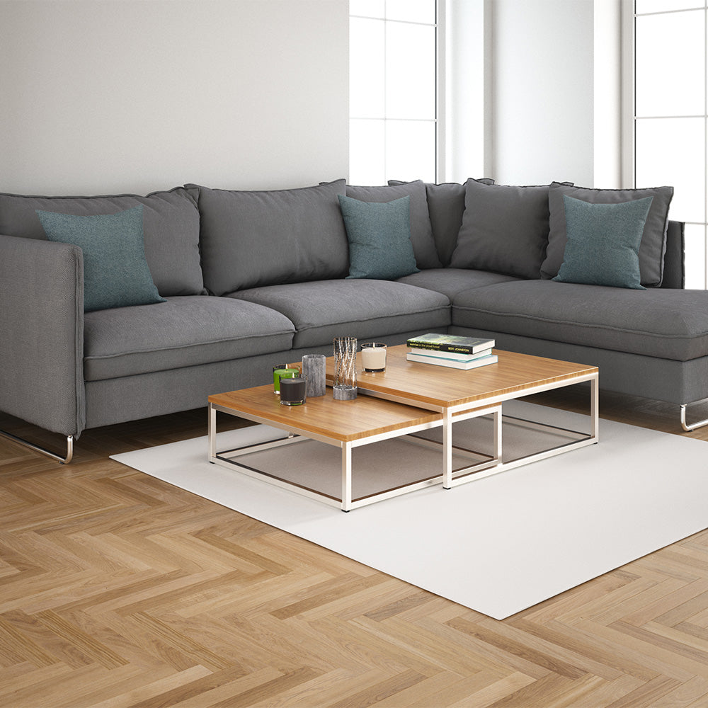 Bright living room lifestyle image showing a gray sectional sofa with teal cushions, a two-tier wood coffee table, and a white rug, highlighting solid textured fabric upholstery.
