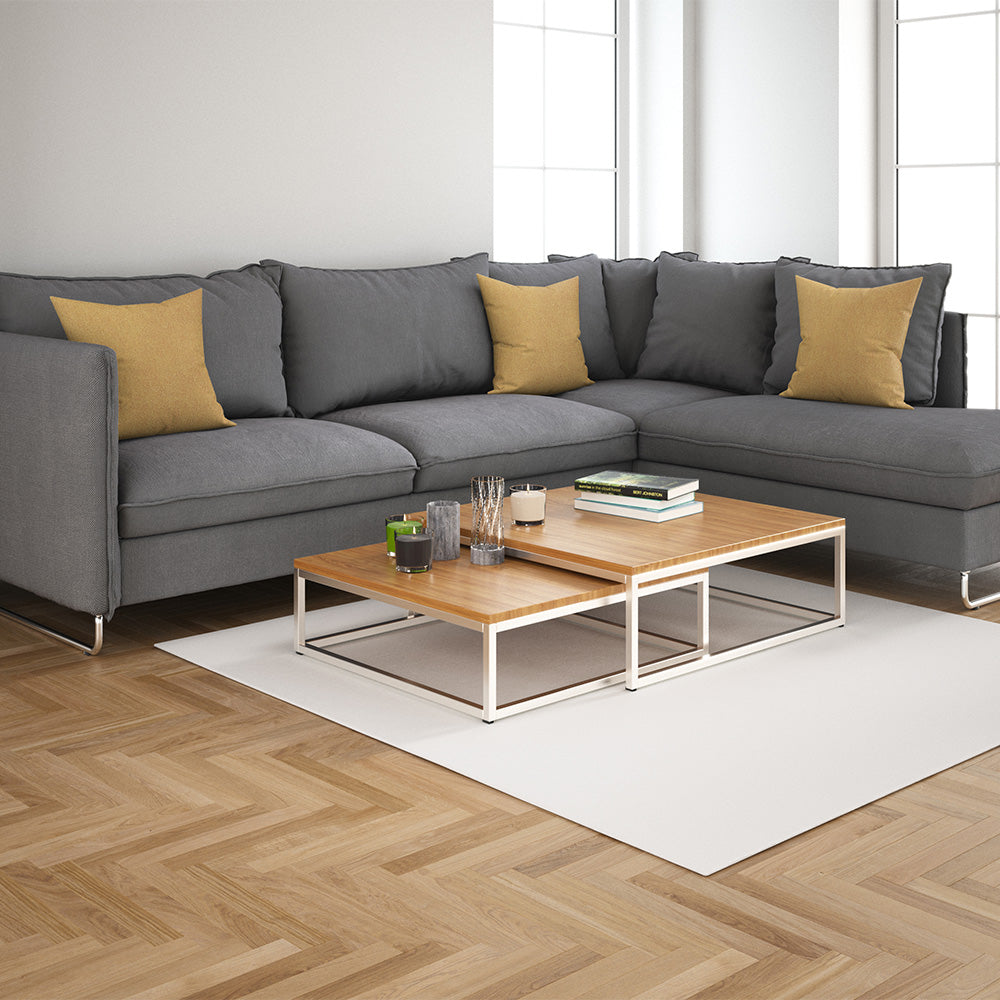 Gray sectional sofa with yellow throw pillows, two wood-topped nesting coffee tables on a white rug in a bright living room.