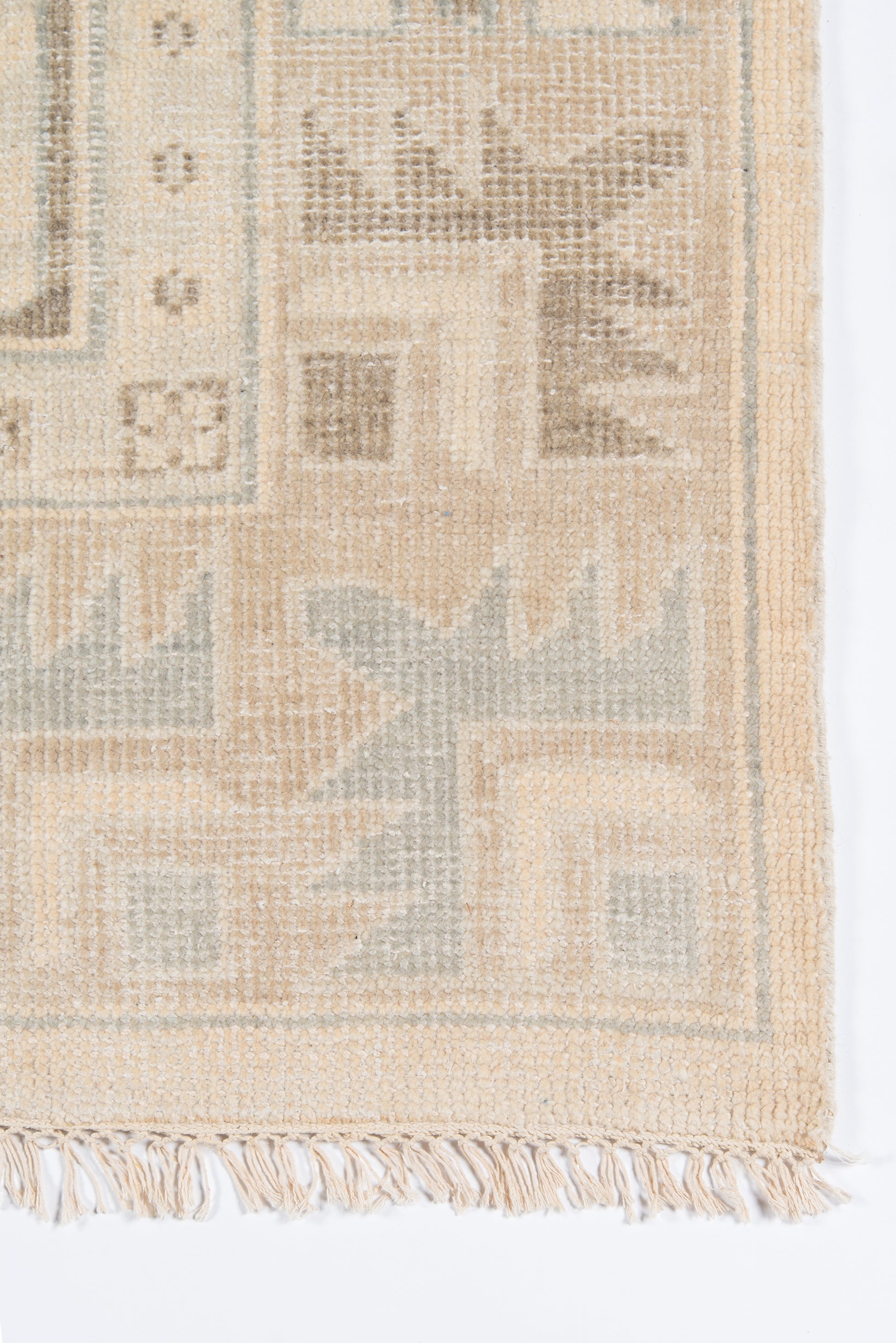 Beige woven rug with light blue-gray geometric motifs and fringed edge; kilim-style decorative floor rug.