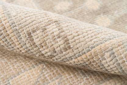 Beige and cream textured woven rug fabric with subtle geometric pattern and plush pile.
