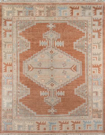 Rust-orange oriental rug with pale blue and ivory geometric central medallion, stepped borders, and fringe.