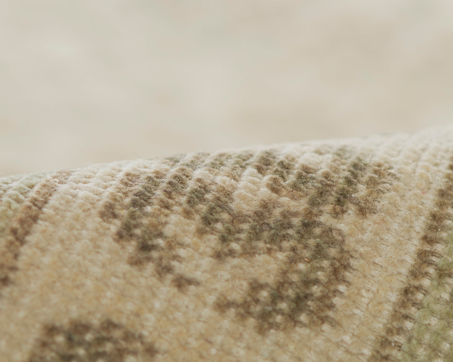 Close-up of a beige woven rug with brown geometric pattern and soft textured fibers.