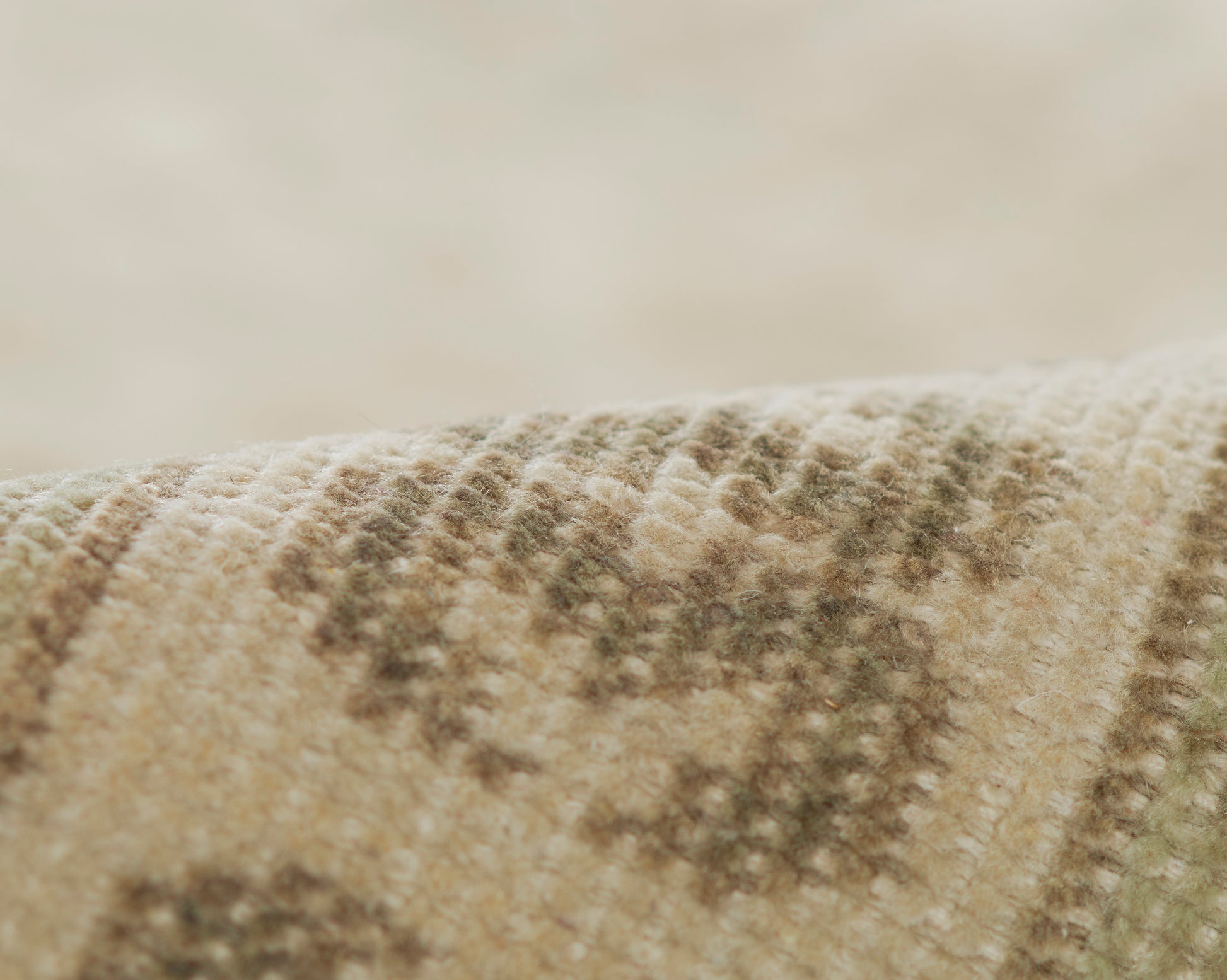 Close-up of a beige textured rug with brown geometric pattern & soft woven fibers.