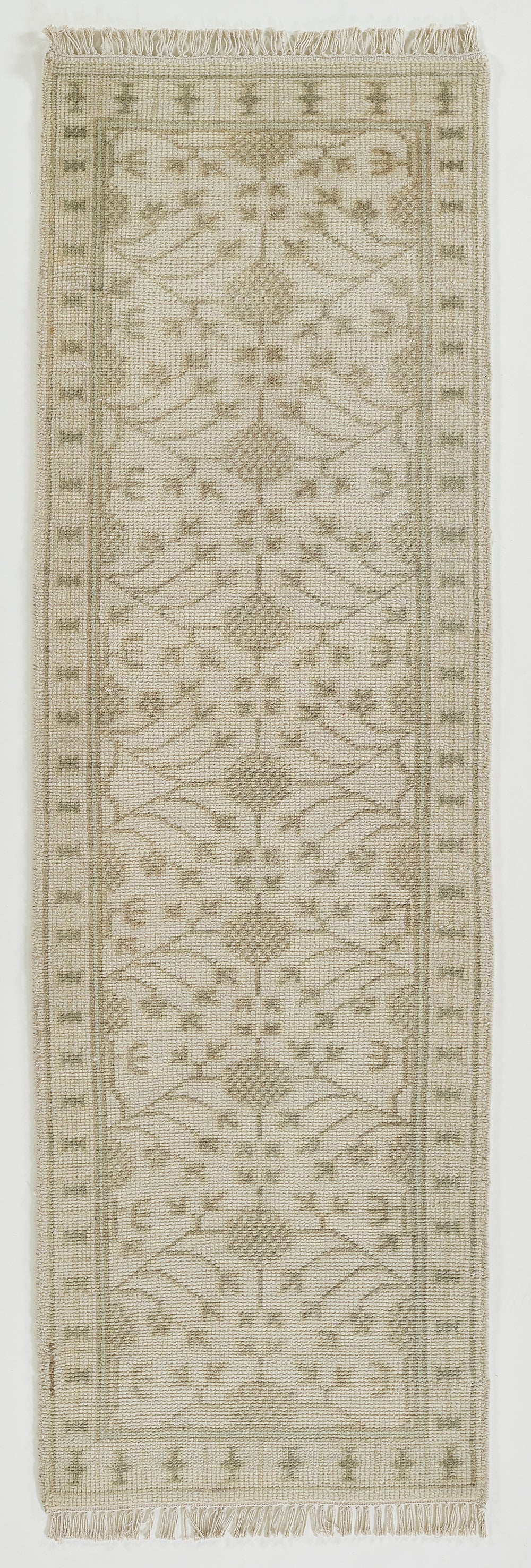 Beige runner rug with subtle gray geometric floral motifs, fringed ends for neutral hall or doorway decor.