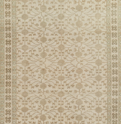Rectangular cream-beige rug with taupe botanical lattice motif and decorative border.