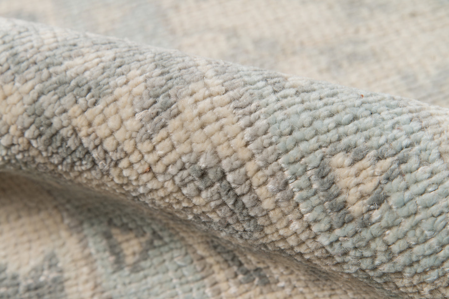 Close-up of plush boucle rug in ivory, gray and blue tones; soft, textured pile for cozy living room decor.