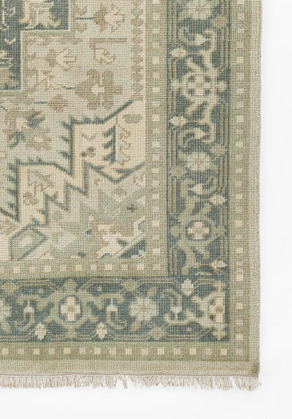 Muted green & beige oriental rug with blue border, intricate geometric floral pattern, fringed edge.