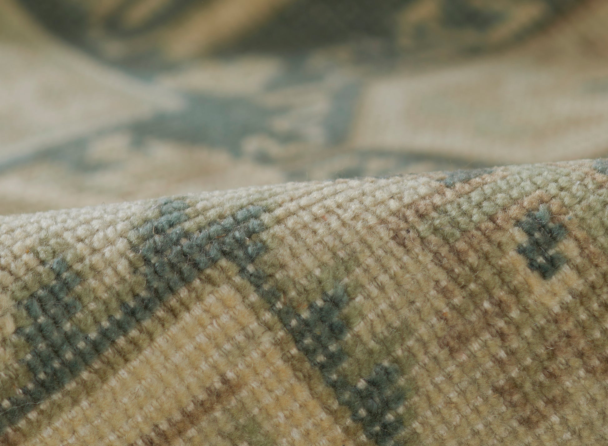 Close-up of a muted green and beige woven runner rug with a geometric motif and soft textured pile.