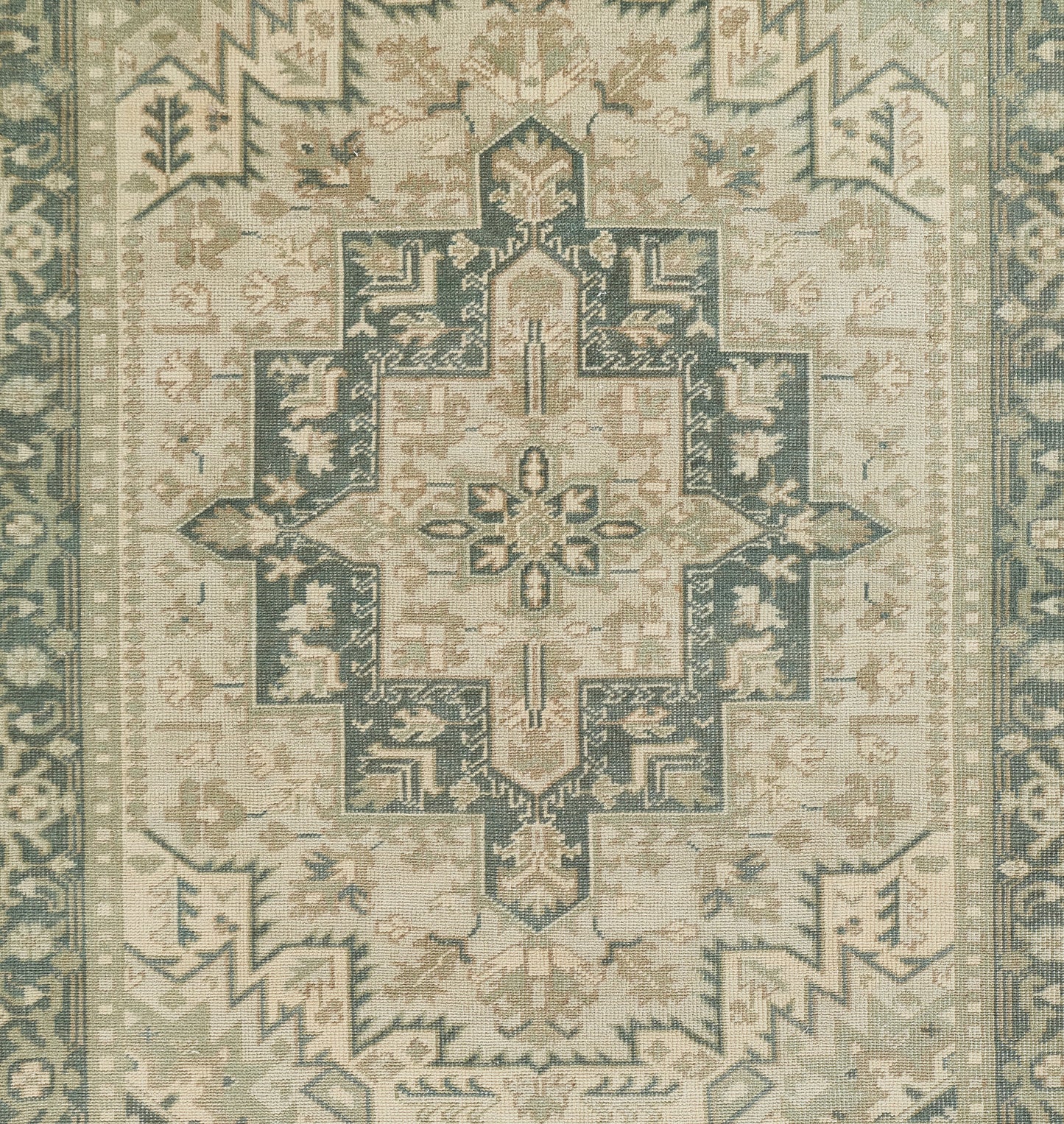 Muted sage, teal and cream oriental rug with a large central cross-shaped medallion and ornate border.