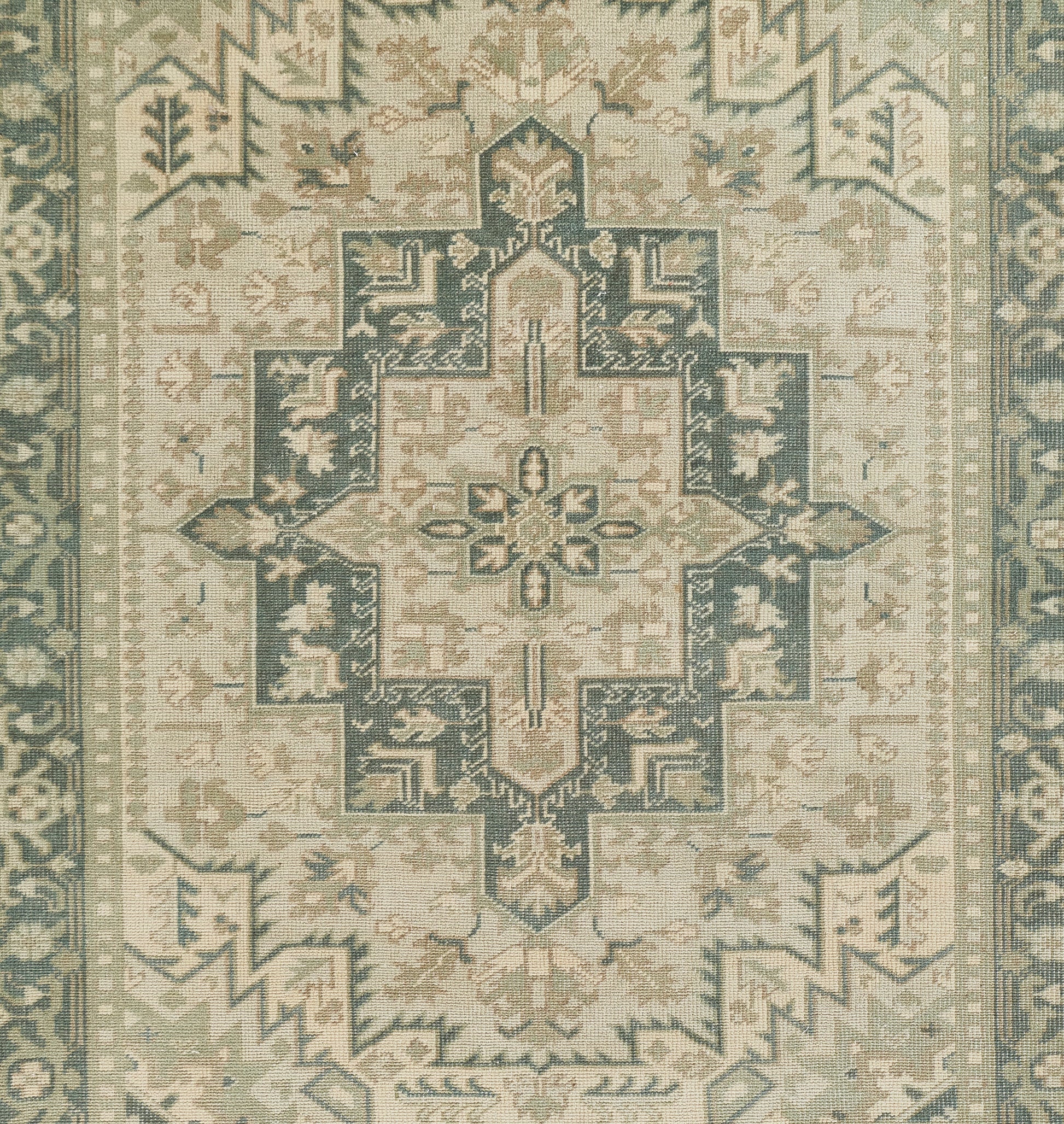 Muted sage, teal and cream oriental rug with a large central cross-shaped medallion and ornate border.