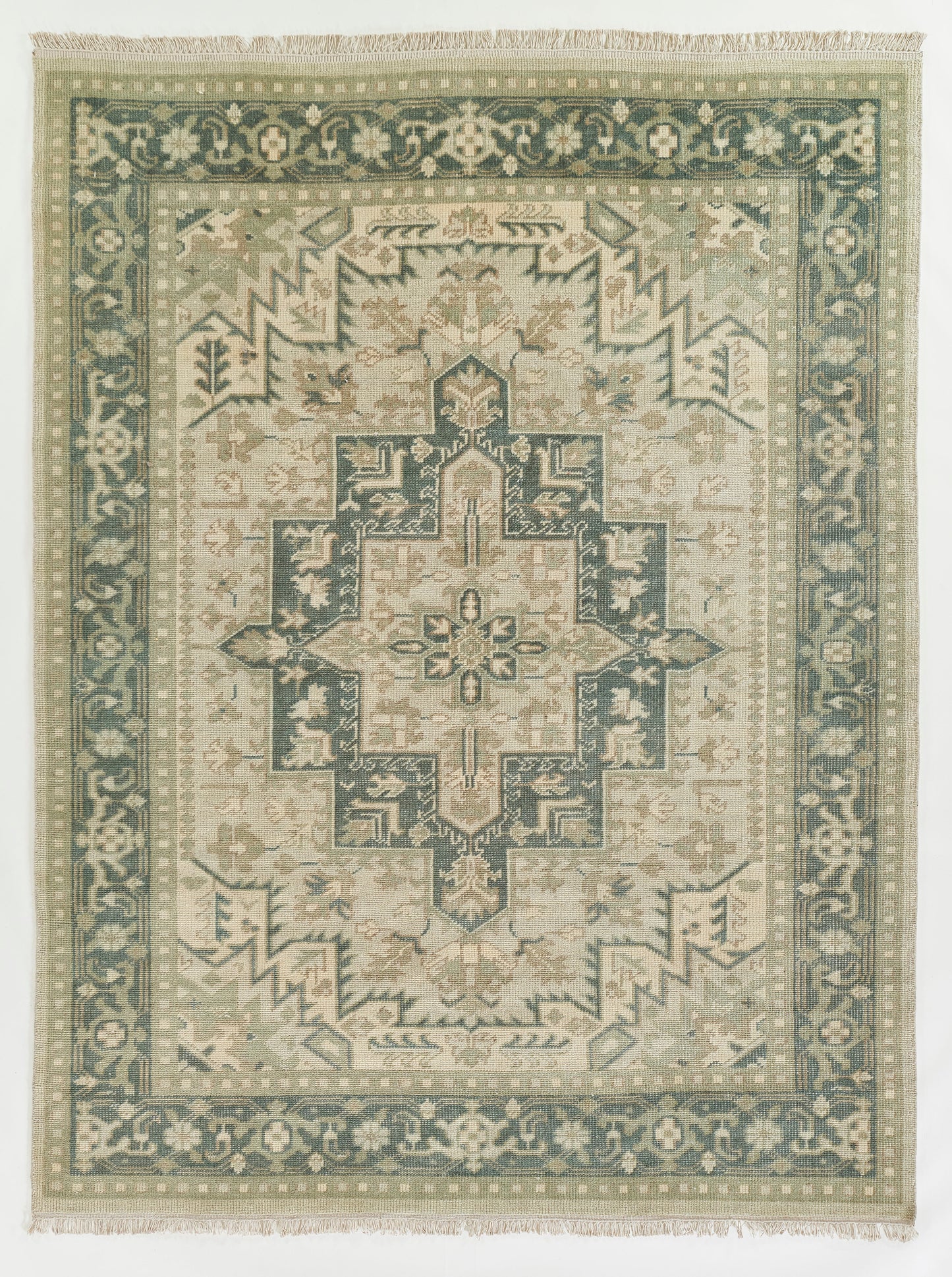 Green & ivory oriental rug with a central geometric medallion, teal border, and fringed ends.