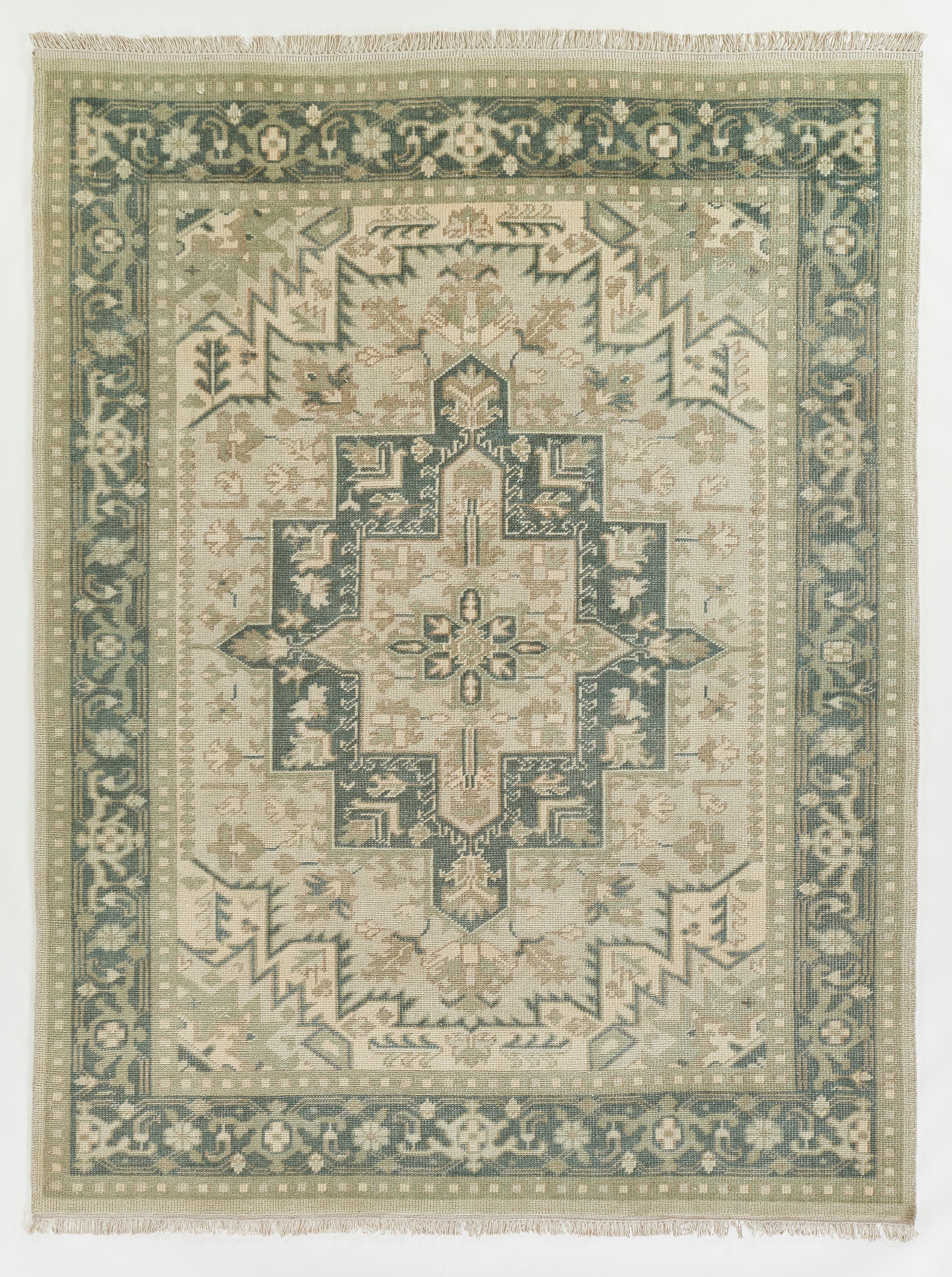 Green & ivory oriental rug with a central geometric medallion, teal border, and fringed ends.