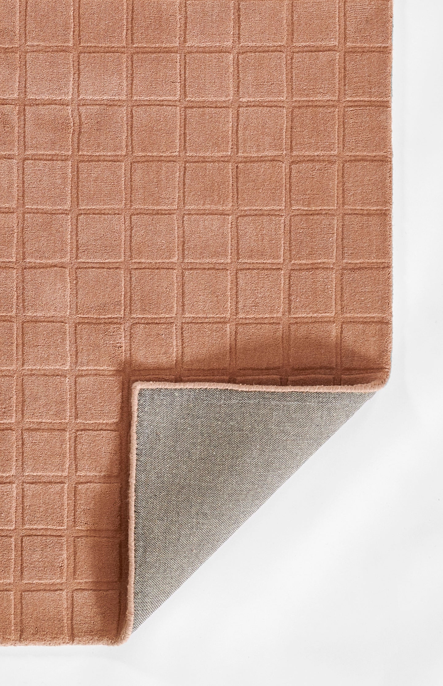 Terracotta grid-textured rug with soft weave; folded corner reveals grey anti-slip backing.