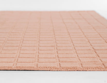 Soft peach area rug with a raised square grid texture.