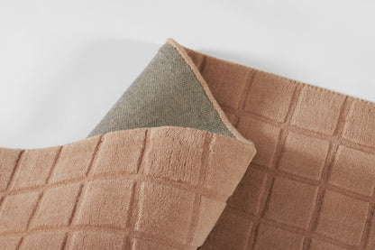 Peach waffle-weave rug with grey underside, square-grid texture, bathroom rug.