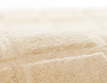 Beige plush terry towels with soft cotton loops, rolled and folded for a cozy bath set.