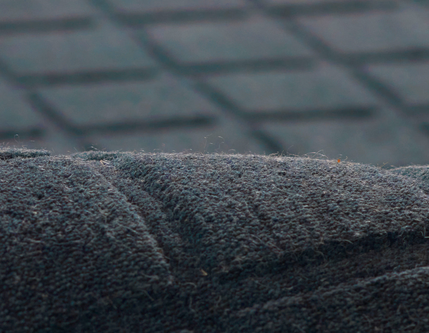 Close-up of a dark navy suede-like rug with nap and a seam, 2' x 3'.