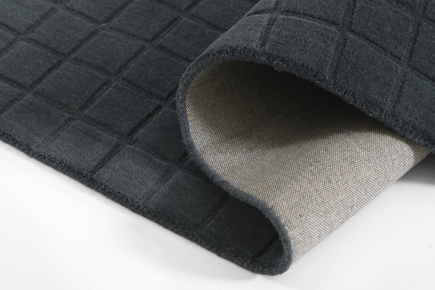 Navy quilted rug with grid stitching, beige underside visible; soft, cushioned floor mat.