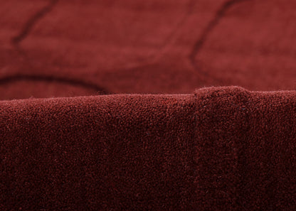 Close-up of burgundy velvet fabric with plush nap and folded edge.