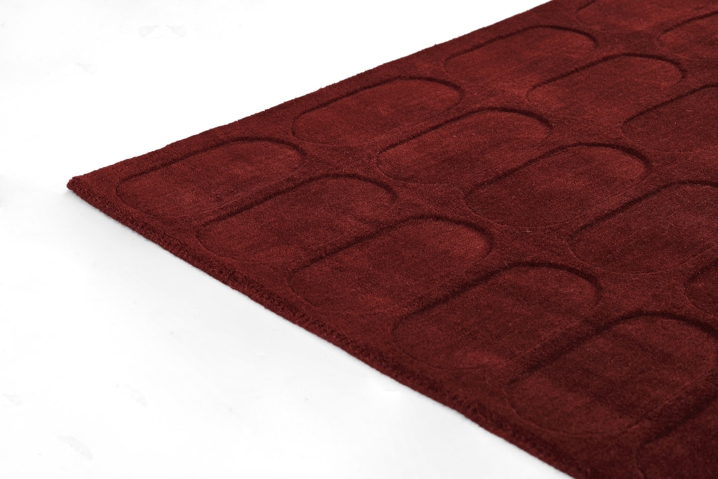 Deep burgundy tufted area rug with a rounded-rectangle pattern; plush low-pile, modern geometric design.