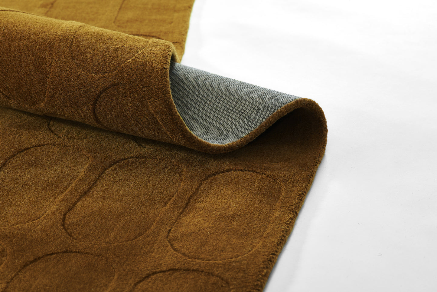 Brown carpet sample with embossed rounded-rectangle pattern, folded to reveal gray backing.