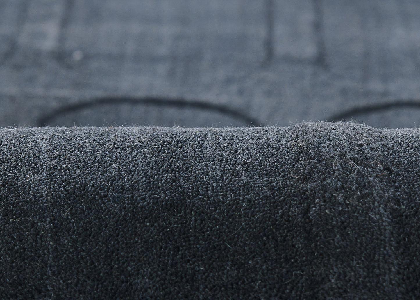 Navy velvet rug close-up with soft nap and rolled edge.