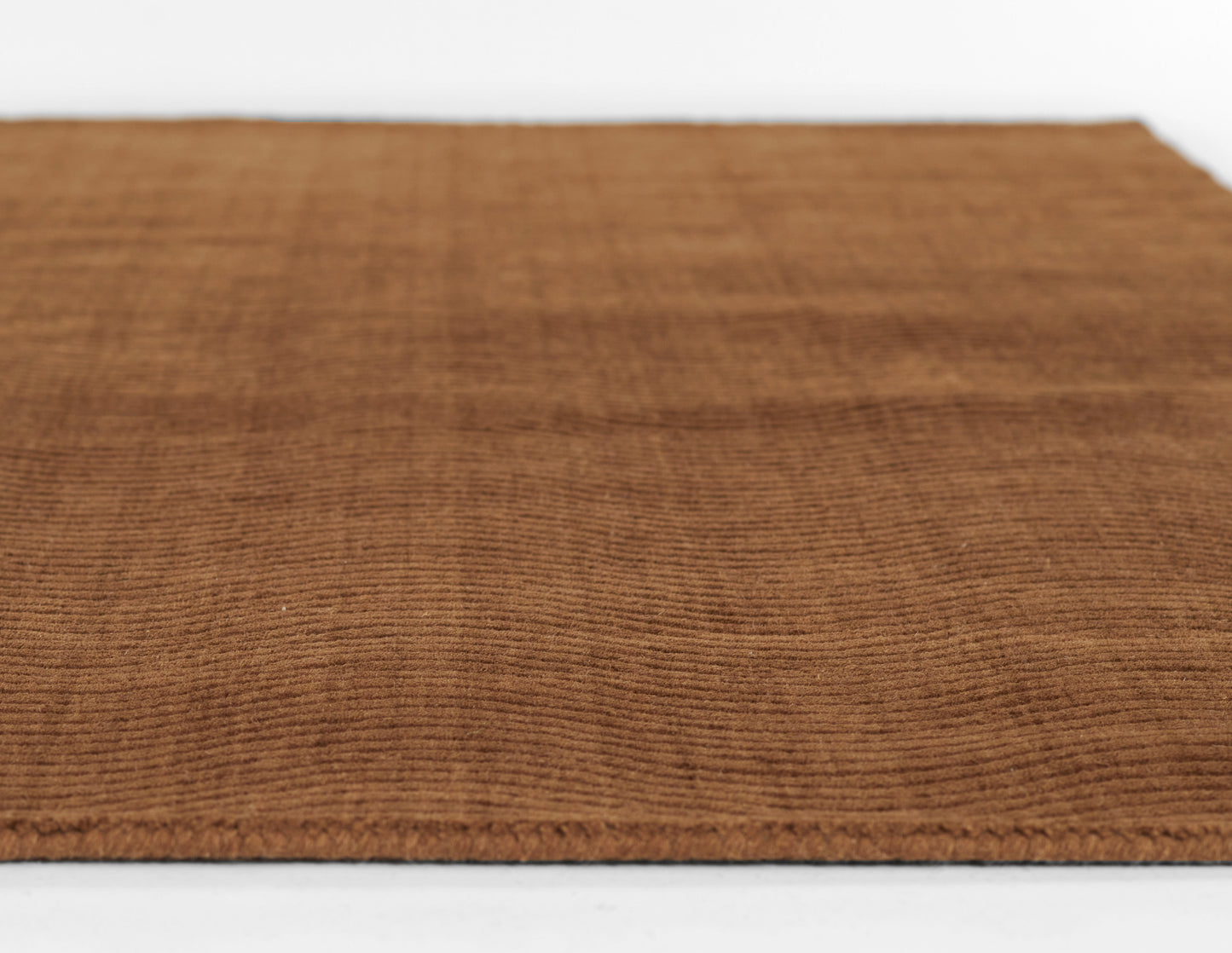 Brown rectangular rug with ribbed corduroy texture, warm woven flooring mat.