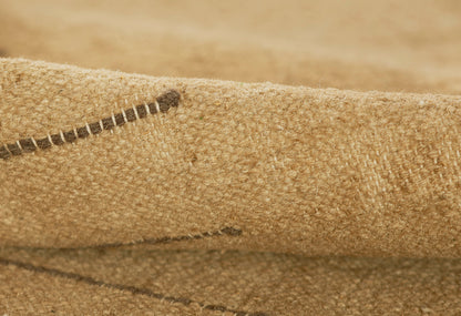 Close-up of beige burlap-like rug texture with visible stitching and rough woven jute fibers.
