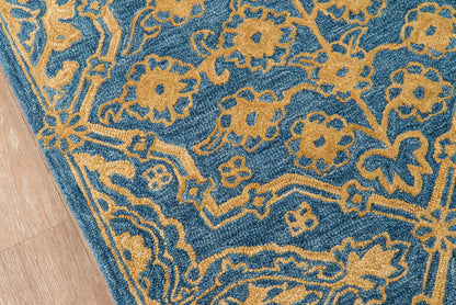 Blue area rug, 8' x 11', with a gold floral and vine pattern on a wooden floor.