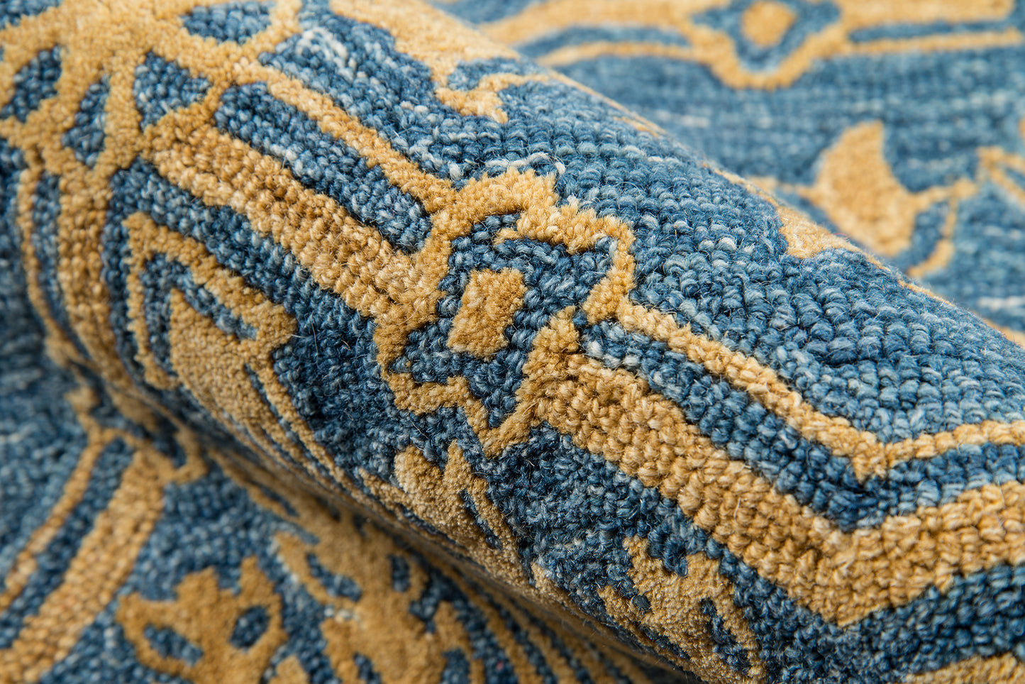 Close-up of a blue and mustard yellow patterned woven rug with a textured pile.
