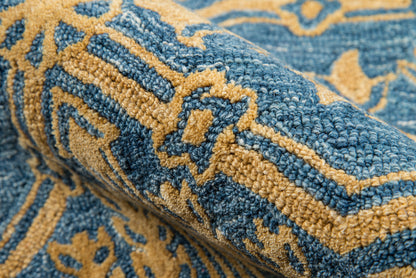 Blue and gold woven rug with ornate geometric floral pattern; thick pile, decorative floor covering.