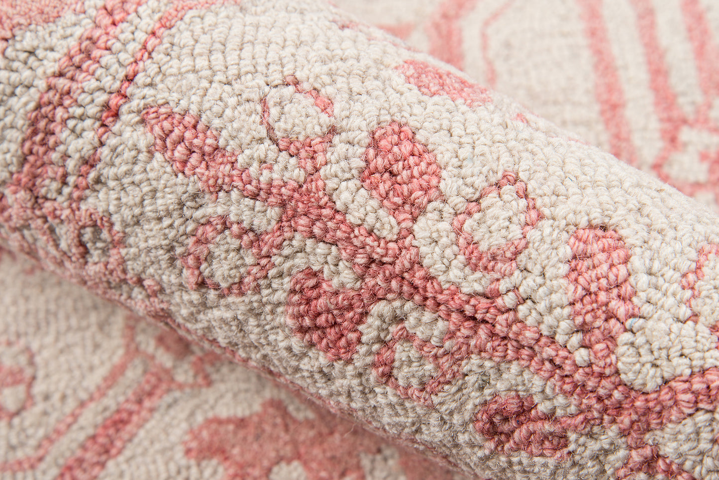 Close-up of a plush pink and cream woven rug with a floral damask pattern and dense loop pile.