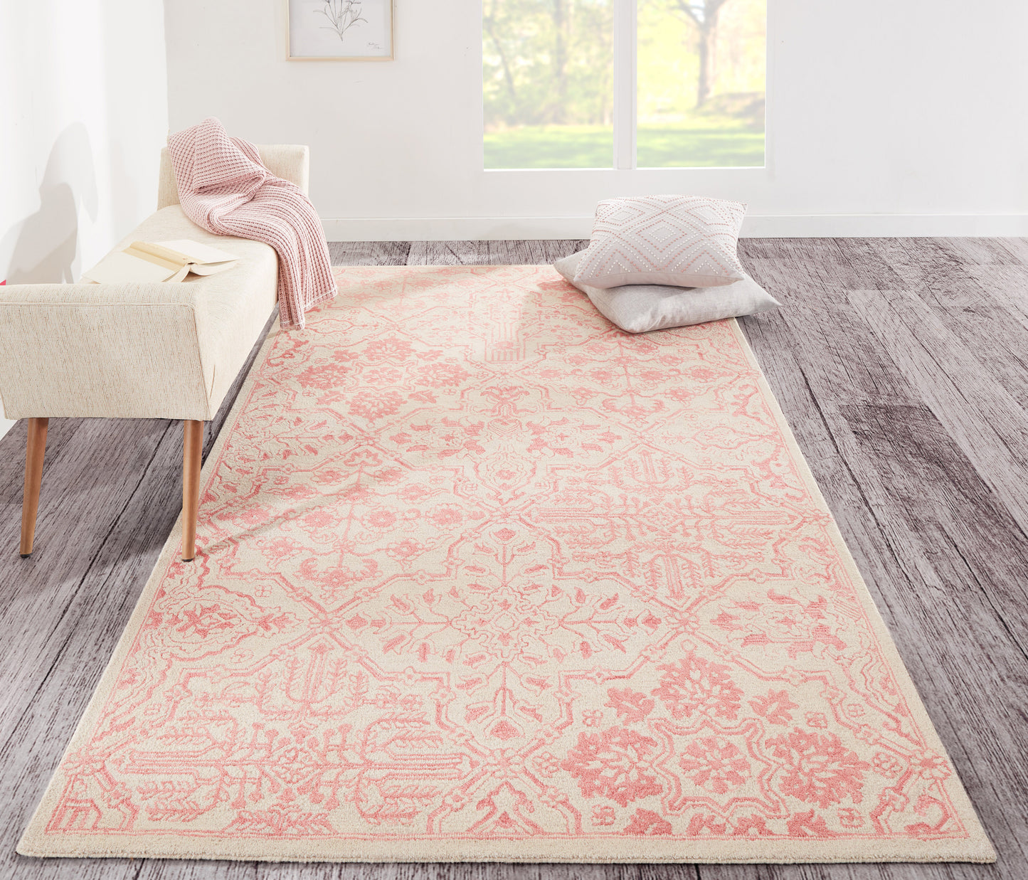 Pink 8' x 10' area rug with a pale peach ornate floral-medallion pattern, placed in a bright living room with a sofa and cushions.