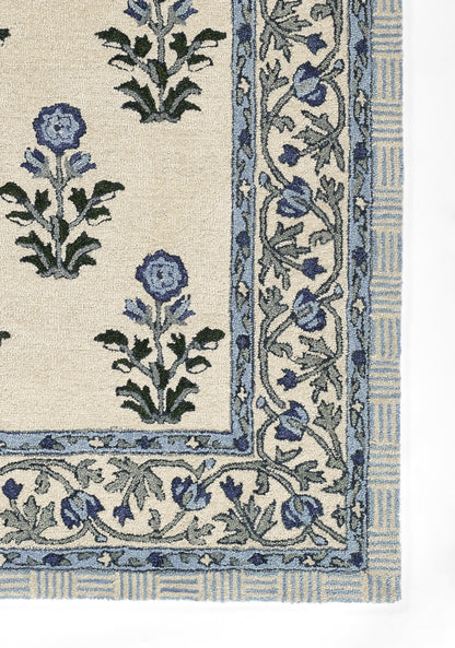 Cream rug with blue floral motifs and a scrolling blue border in a traditional pattern.