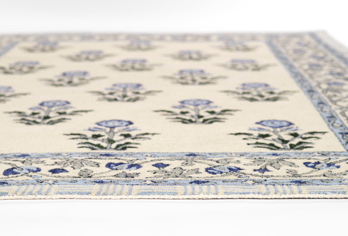 Cream flatwoven rug with blue floral bouquets and a blue patterned border, close-up view.