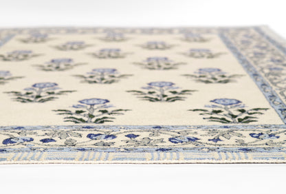Cream flatwoven rug with blue floral bouquets and a blue patterned border, close-up view.