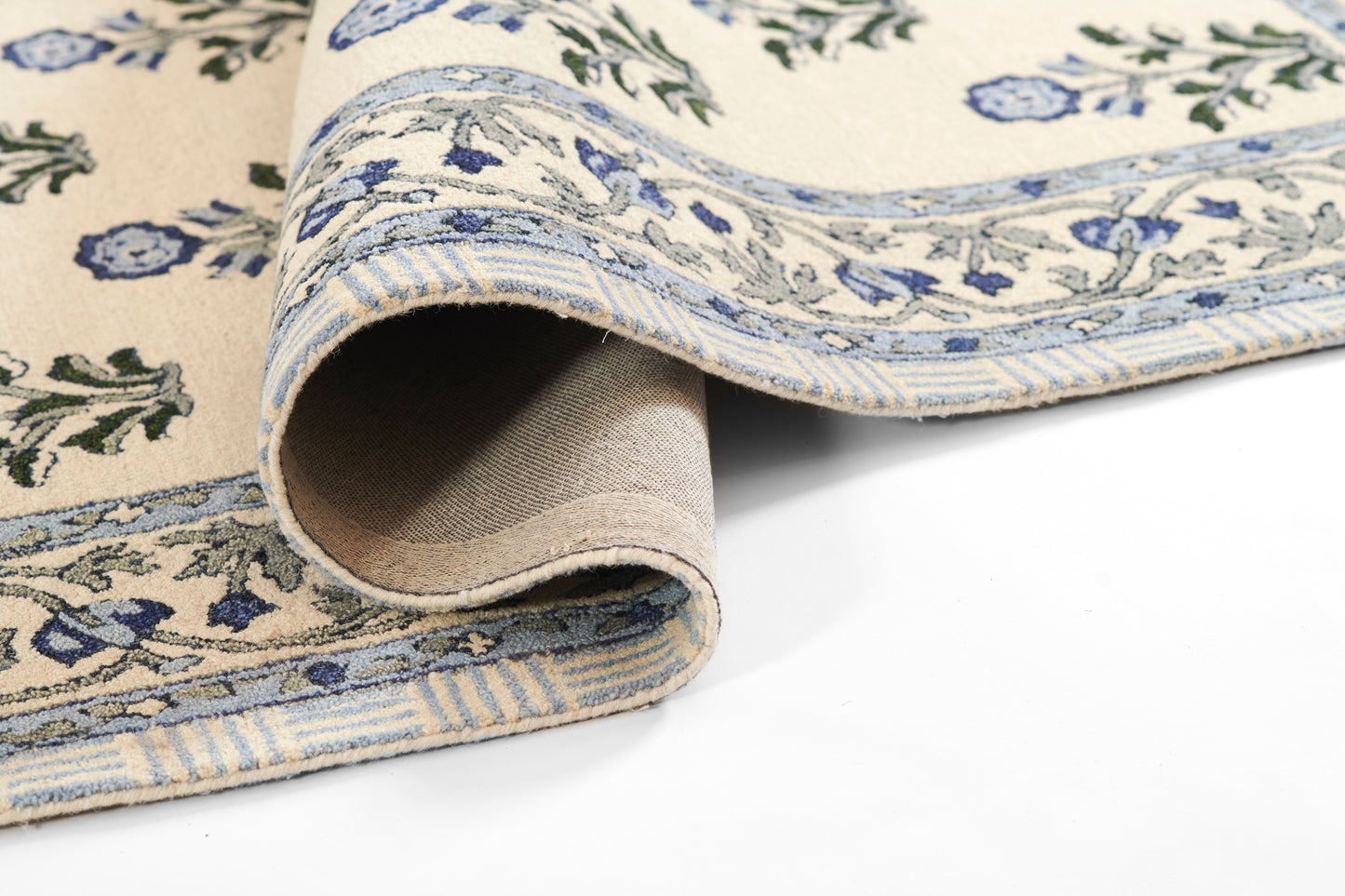 Cream and blue floral patterned cotton rug, rolled edge reveals beige backing.