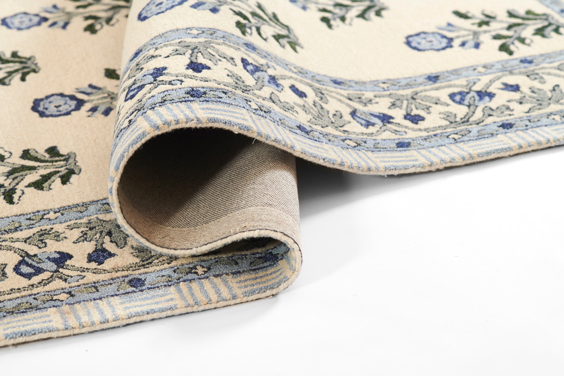 Cream and blue floral patterned cotton rug, rolled edge reveals beige backing.