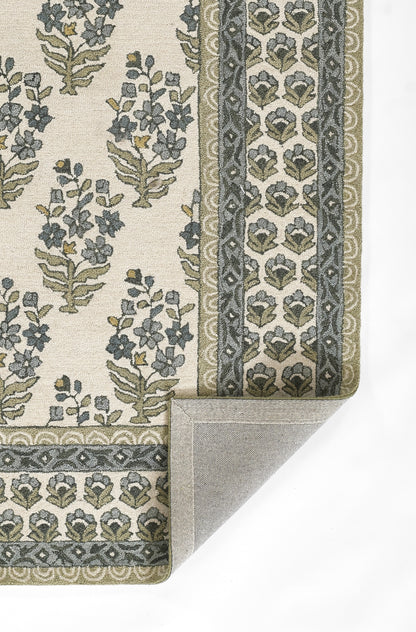 Floral patterned rug with cream base, blue-green and olive motifs, decorative borders; folded corner showing backing.