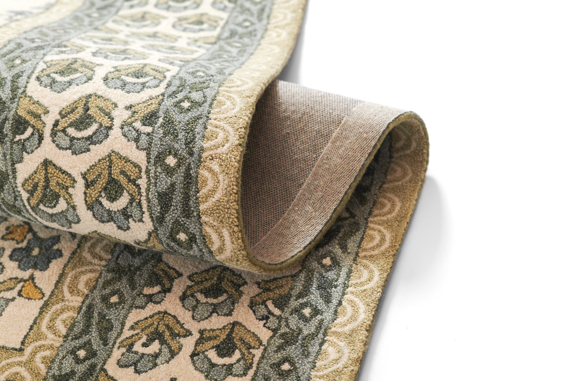 Beige woven area rug with green-gray floral border, rolled at the edge.
