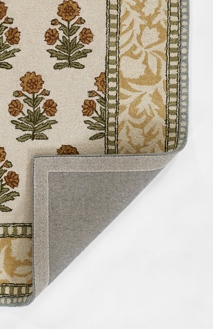 Beige Cotswold-style runner rug with gold floral motifs and olive-green border; folded corner reveals grey back.