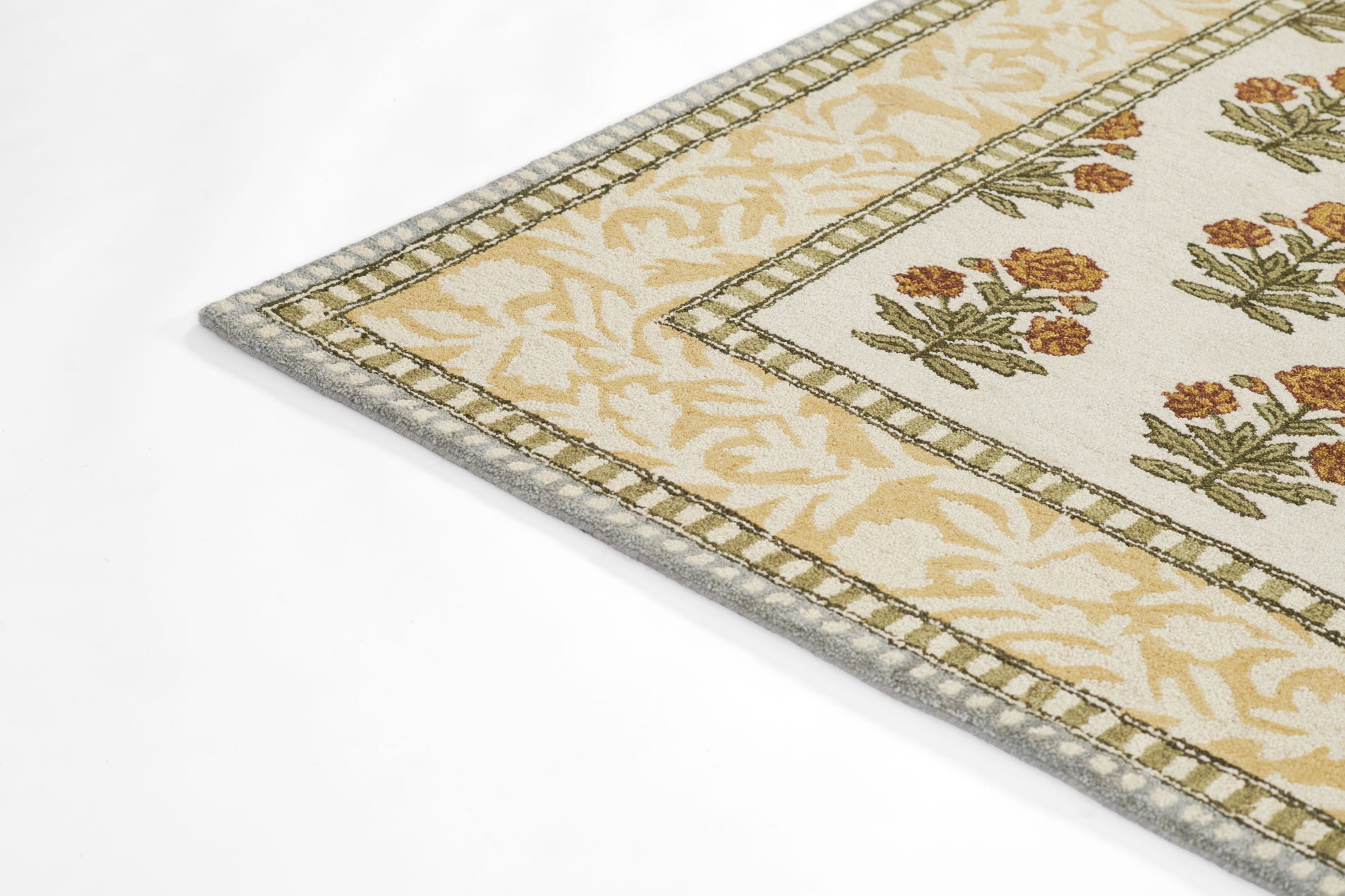 Rectangular cream rug with pale yellow leaf border & brown-orange floral motifs; gray edge trim.