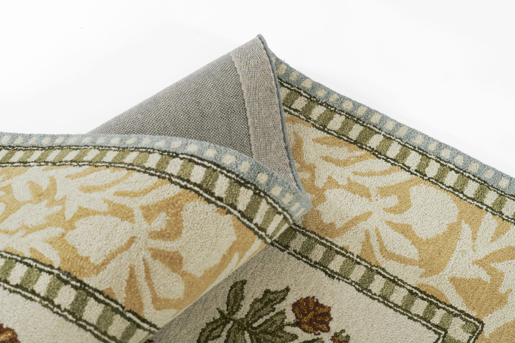 Decorative woven throw with cream/gold floral pattern and olive-green border; folded corner reveals grey backing.